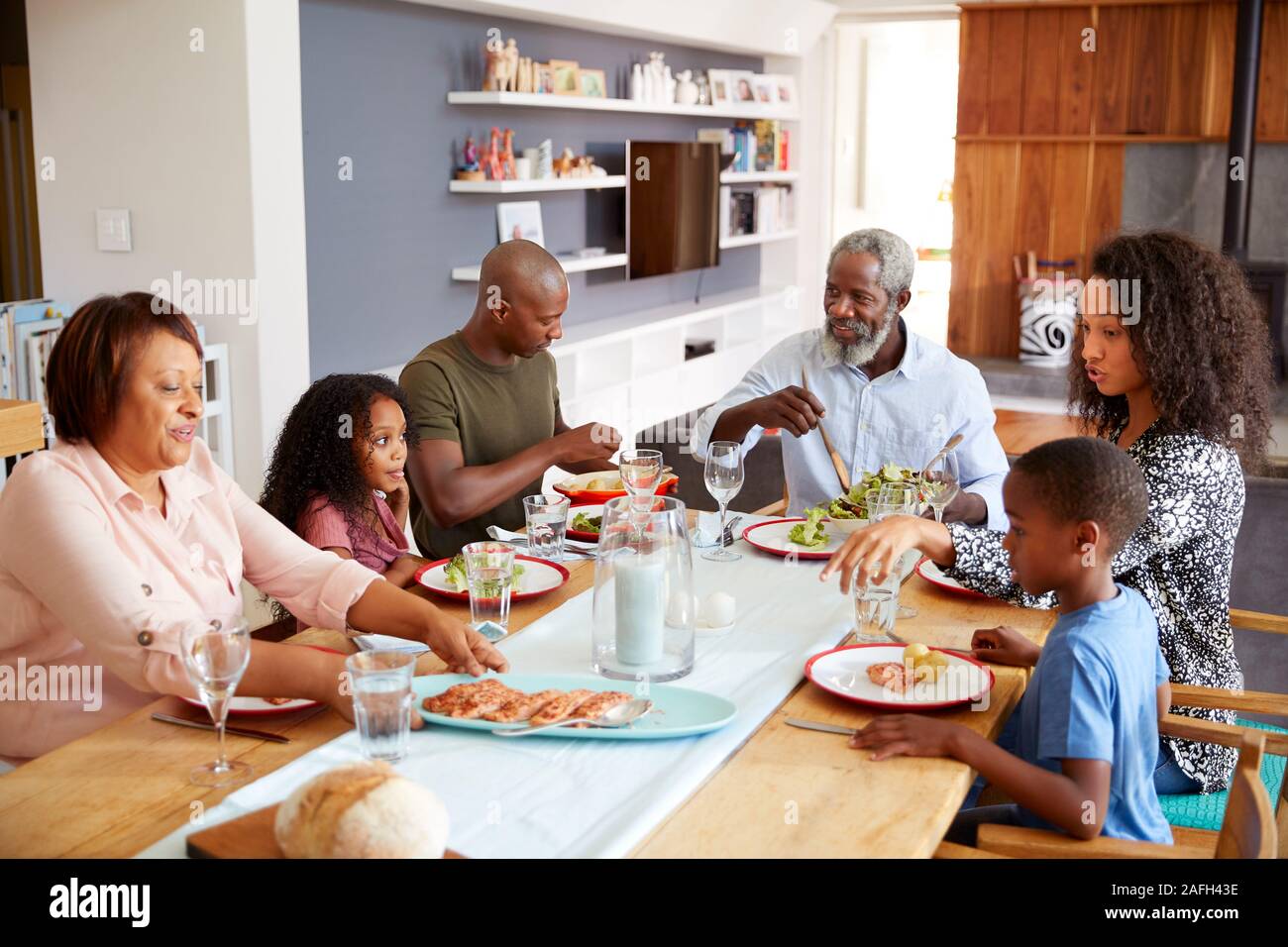 Multi-Generation Familie sitzt um den Tisch zu Hause genießen Mahlzeit zusammen Stockfoto