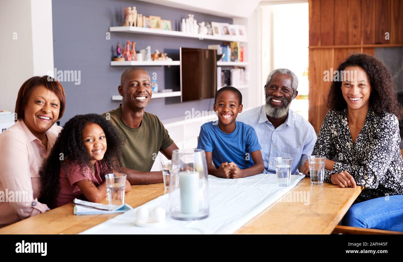 Portrait von Multi-Generation Familie zusammen um den Tisch zu Hause genießen Essen sitzen Stockfoto