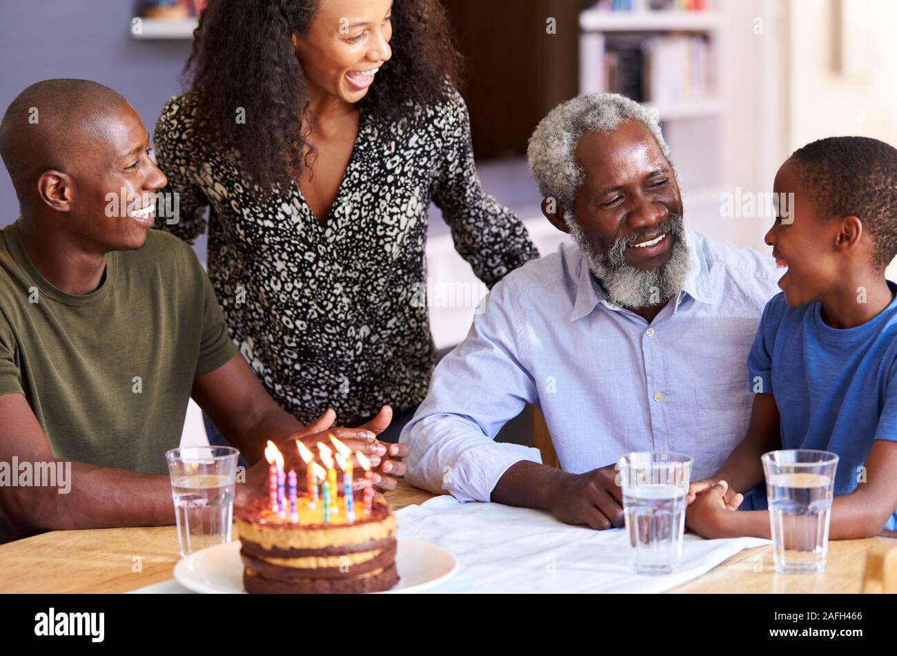 Multi-Generation Familie feiert Geburtstag der Großväter zu Hause mit Kuchen und Kerzen Stockfoto