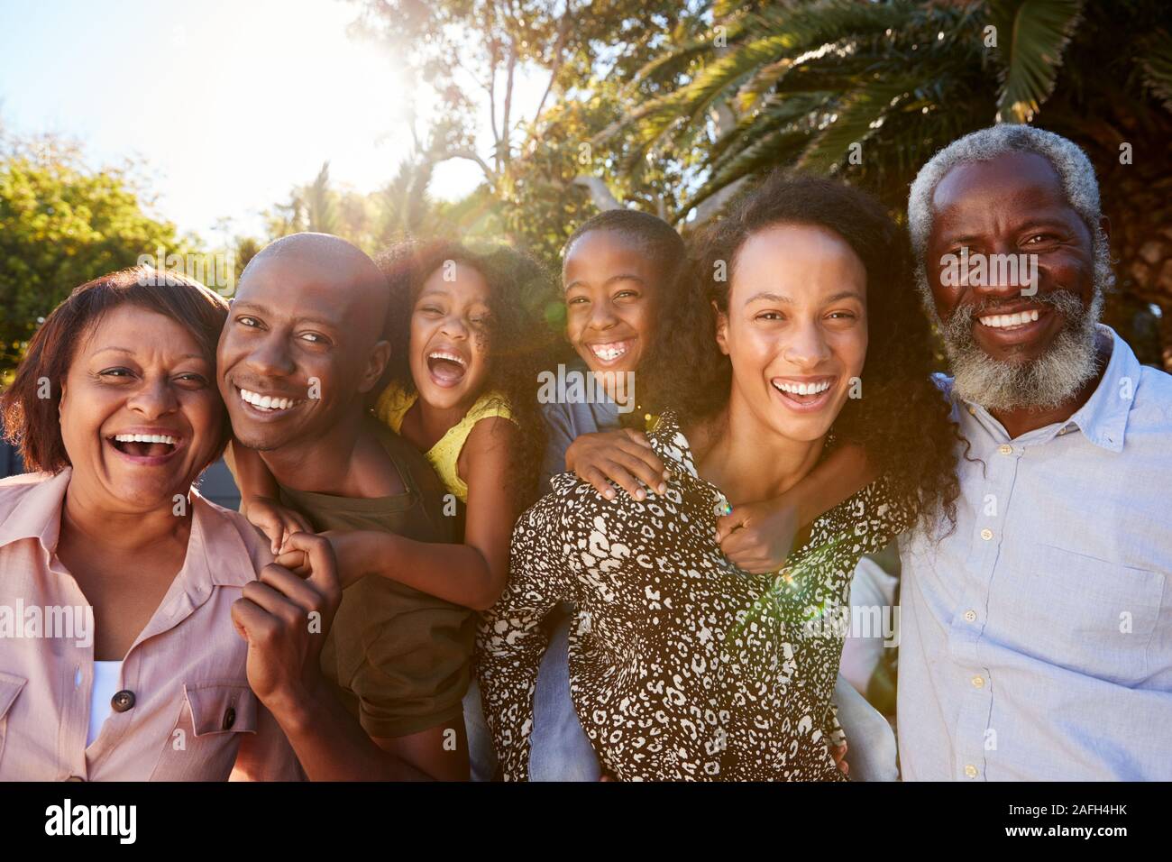 Outdoor Portrait von Multi-Generation Familie im Garten zu Hause gegen das Abfackeln von Sun Stockfoto
