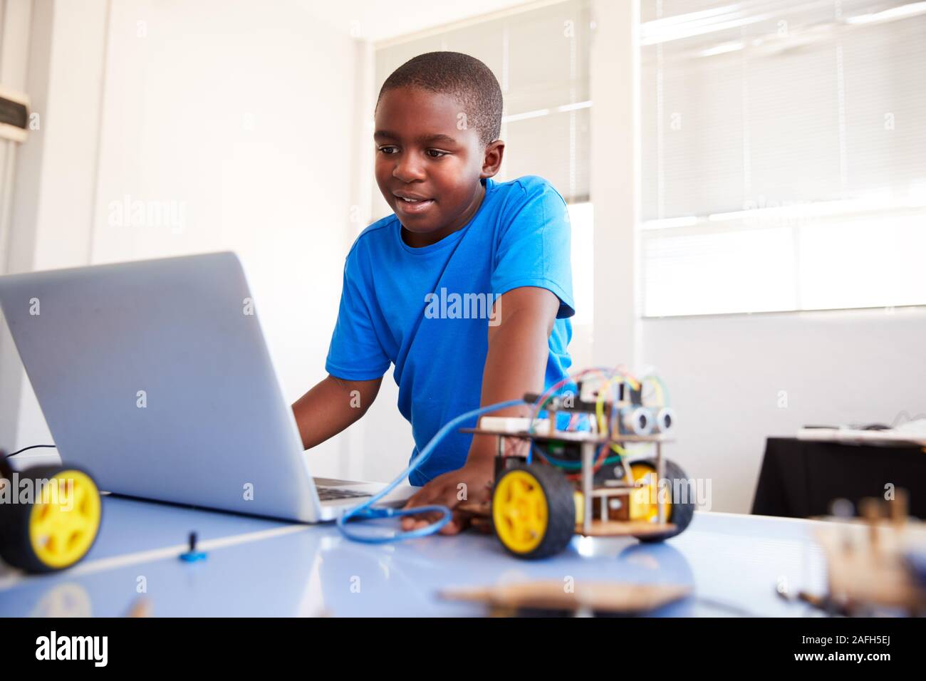 Männliche Schüler Bauen und Programmieren Roboter Fahrzeug nach der Schule Computer Coding Klasse Stockfoto