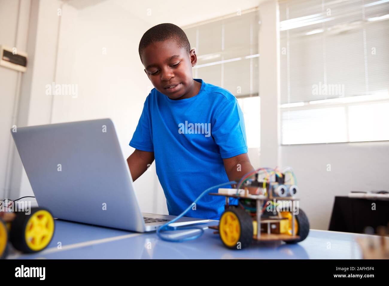Männliche Schüler Bauen und Programmieren Roboter Fahrzeug nach der Schule Computer Coding Klasse Stockfoto