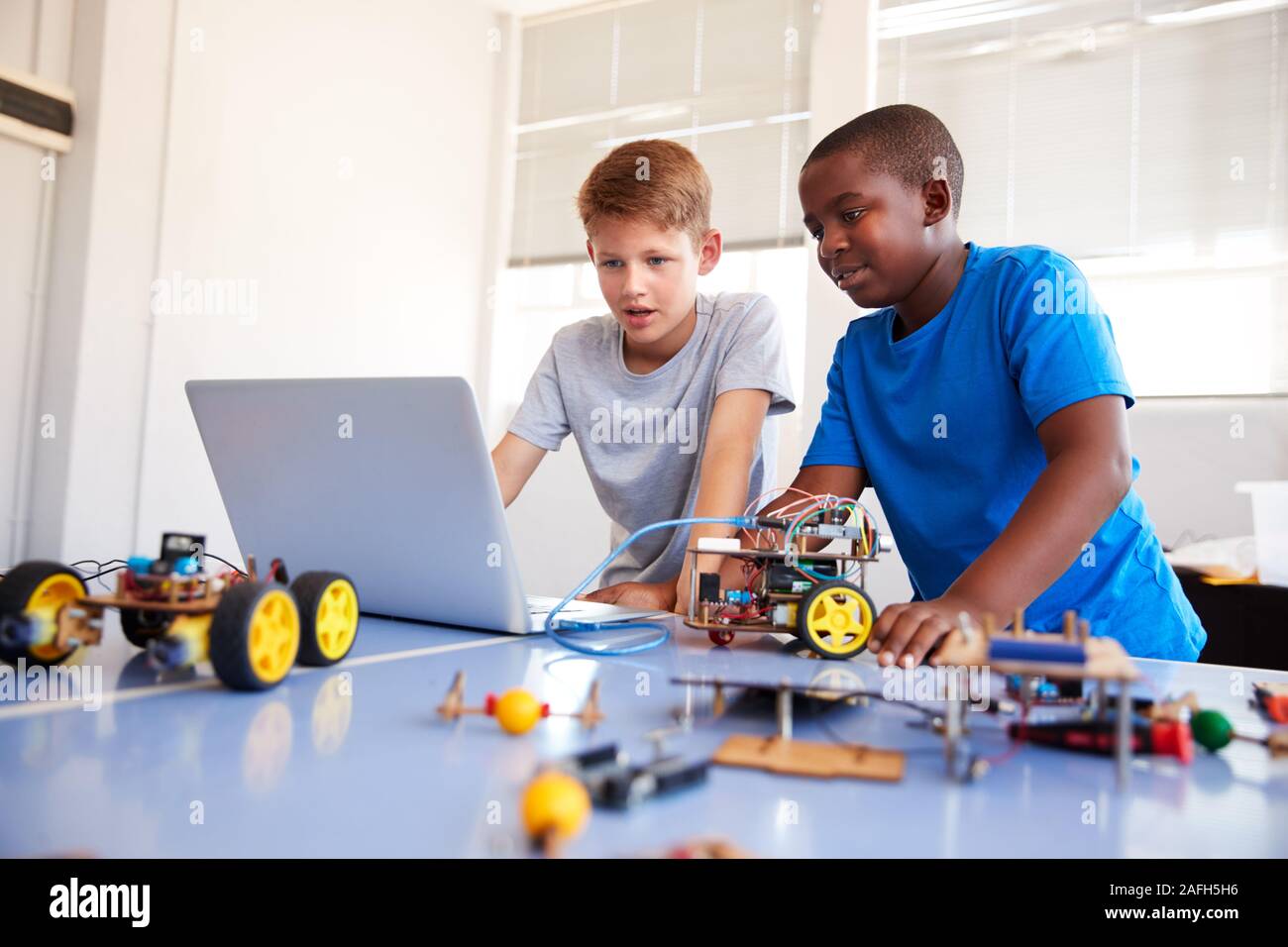 Zwei männliche Schüler Bauen und Programmieren Roboter Fahrzeug nach der Schule Computer Coding Klasse Stockfoto