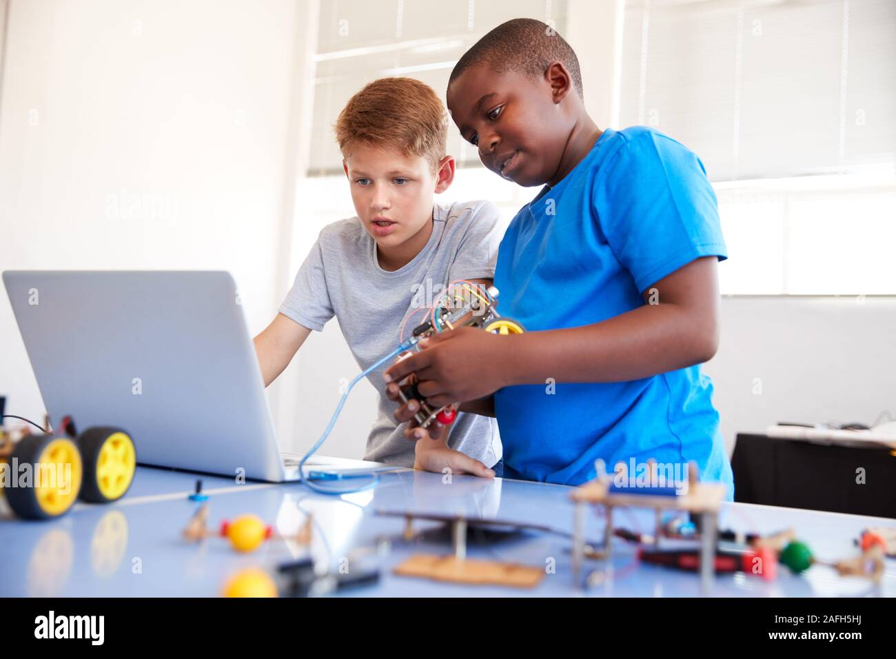 Zwei männliche Schüler Bauen und Programmieren Roboter Fahrzeug nach der Schule Computer Coding Klasse Stockfoto