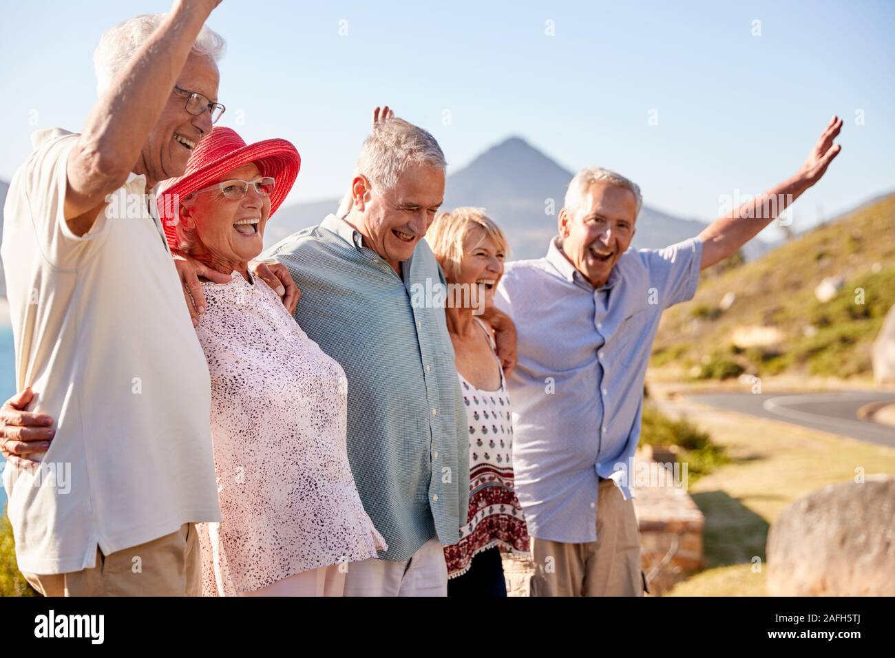 Ältere Freunde besuchen touristische Sehenswürdigkeit auf Gruppe Urlaub mit erhobenen Armen Stockfoto