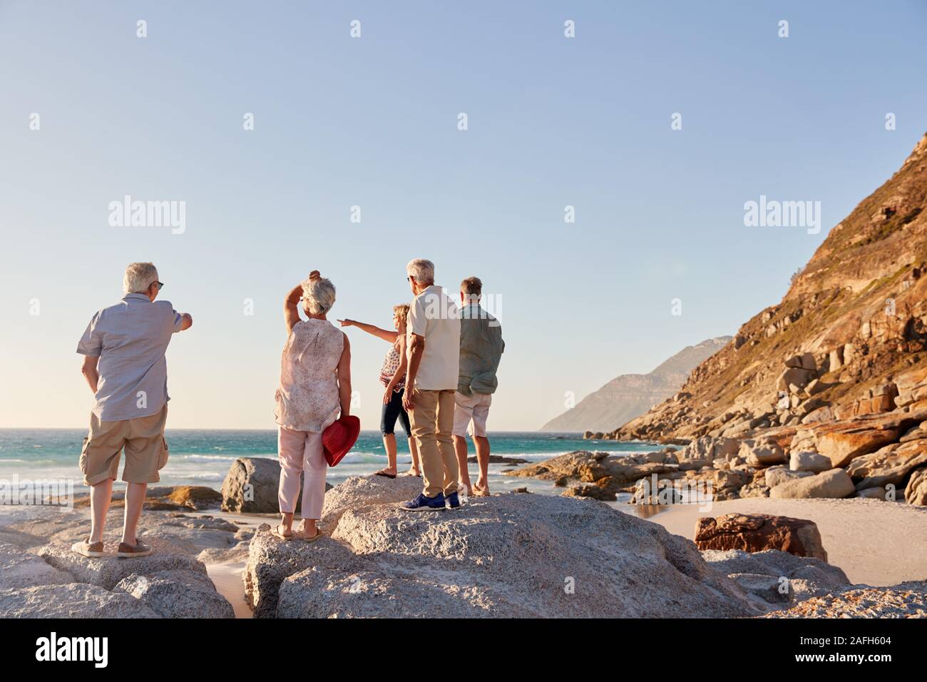 Ansicht der Rückseite des Älteren Freunde stehen auf Felsen auf Sommer Gruppe Ferienhäuser mit Meerblick Stockfoto Ansicht der Rückseite des Älteren Freunde stehen auf Felsen auf Sommer Gruppe Ferienhäuser mit Meerblick Stockfoto