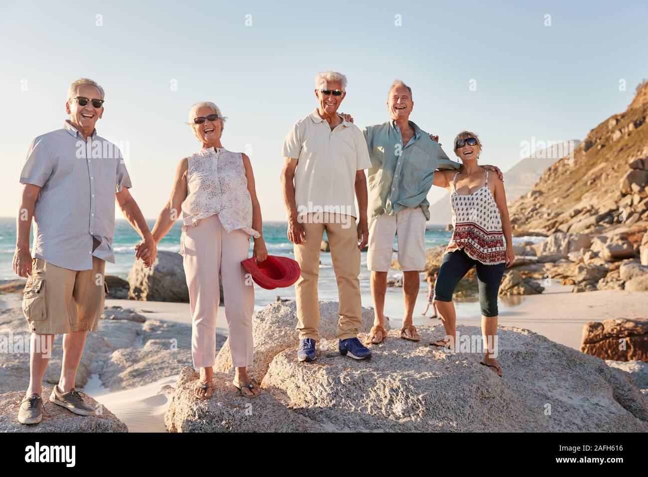 Portrait von älteren Freunde stehen auf Felsen auf dem Seeweg durch Sommer Gruppe Ferienhäuser Stockfoto