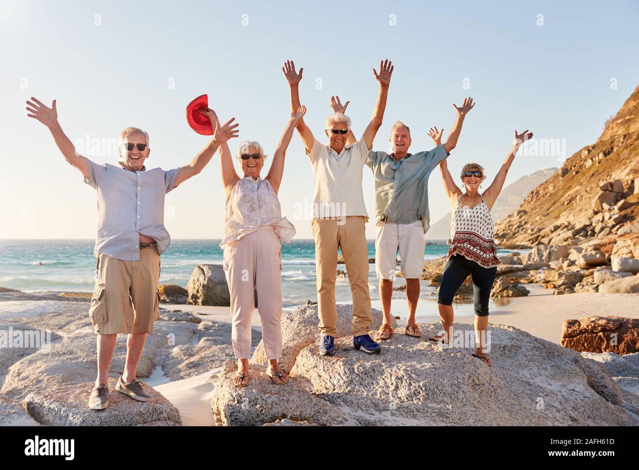 Portrait von älteren Freunde stehen auf Felsen auf dem Seeweg durch Sommer Gruppe Urlaub mit ausgestreckten Armen Stockfoto