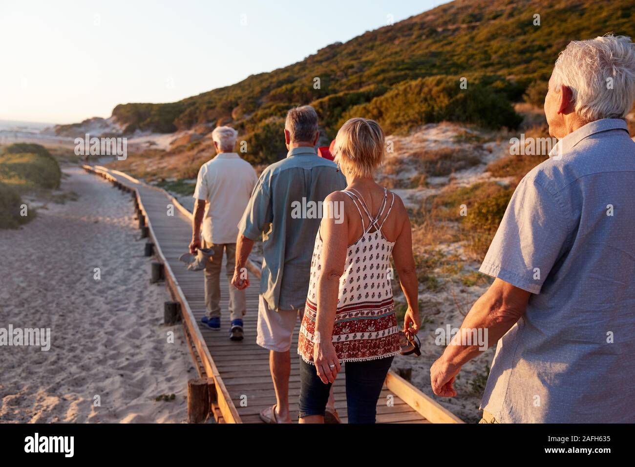 Gruppe von älteren Freunden zu Fuß entlang der Promenade am Strand im Sommer Gruppe Ferienhäuser Stockfoto