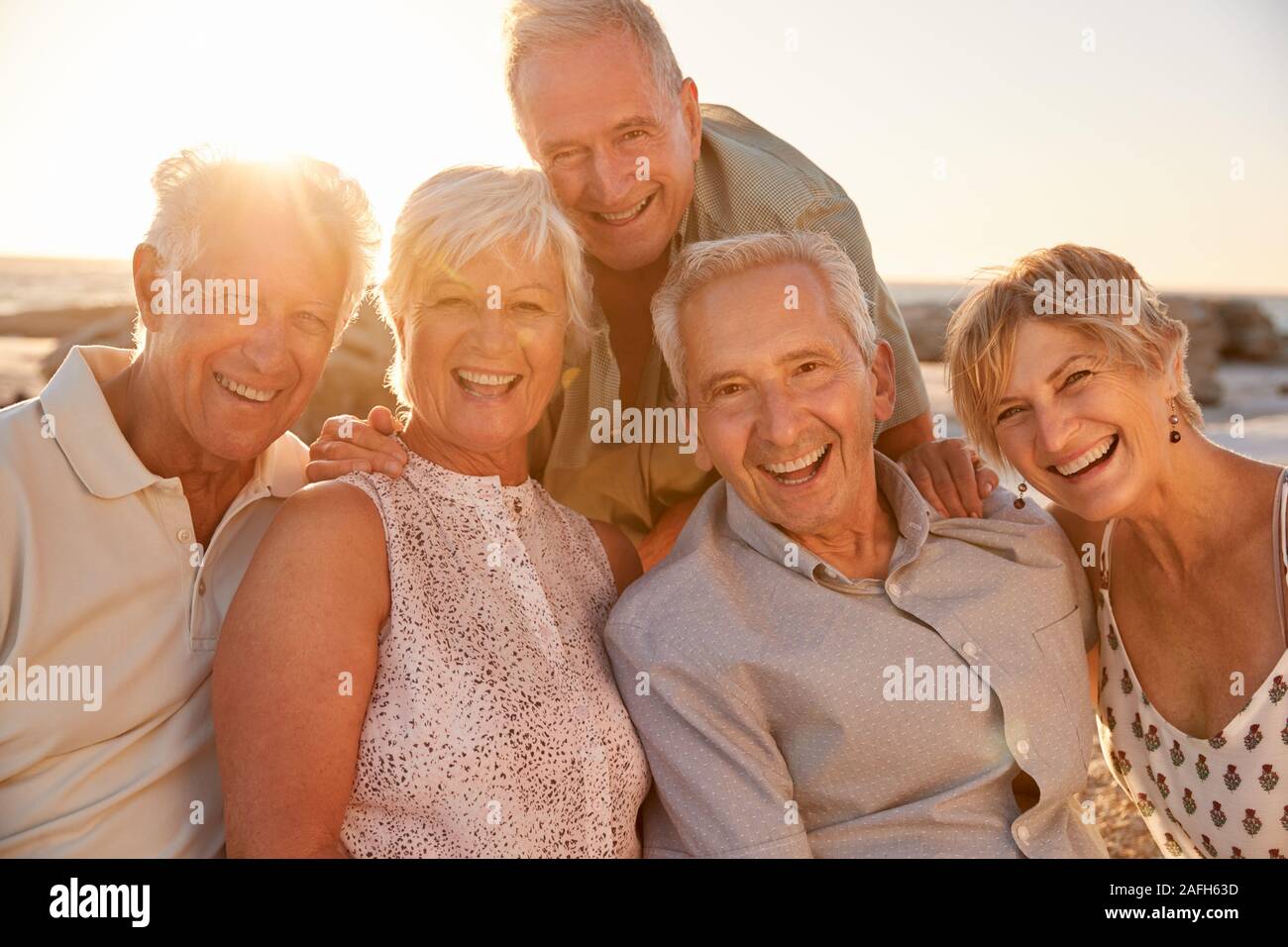 Portrait von älteren Freunden sitzen auf den Felsen auf dem Seeweg durch Sommer Gruppe Ferienhäuser Stockfoto Portrait von älteren Freunden sitzen auf den Felsen auf dem Seeweg durch Sommer Gruppe Ferienhäuser Stockfoto