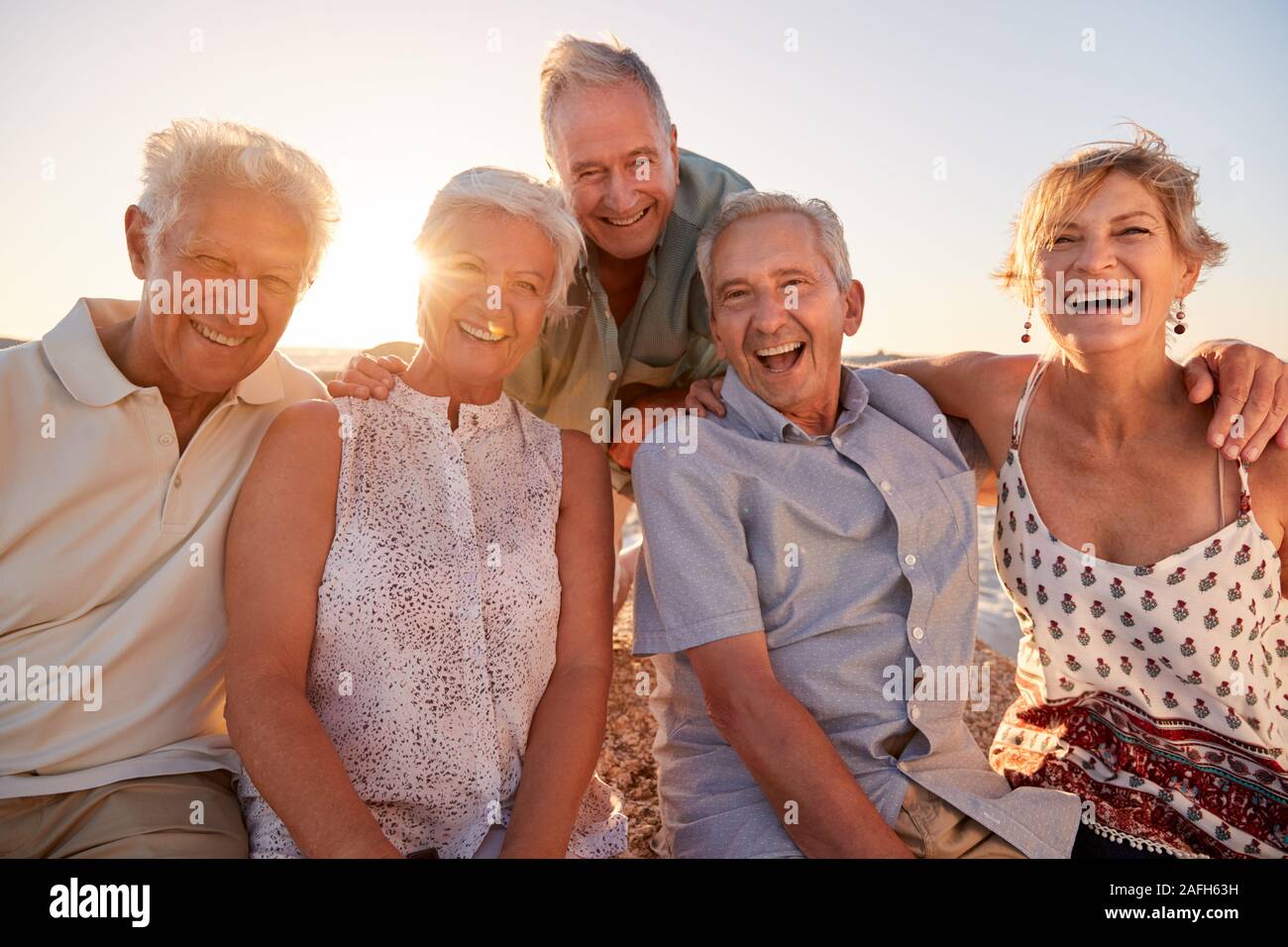 Portrait von älteren Freunden sitzen auf den Felsen auf dem Seeweg durch Sommer Gruppe Ferienhäuser Stockfoto Portrait von älteren Freunden sitzen auf den Felsen auf dem Seeweg durch Sommer Gruppe Ferienhäuser Stockfoto