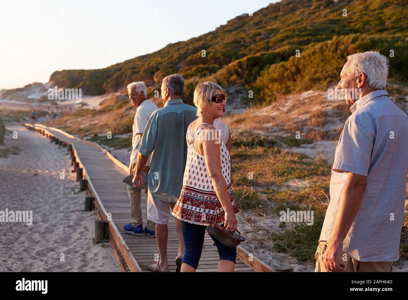 Gruppe von älteren Freunden zu Fuß entlang der Promenade am Strand im Sommer Gruppe Ferienhäuser Stockfoto Gruppe von älteren Freunden zu Fuß entlang der Promenade am Strand im Sommer Gruppe Ferienhäuser Stockfoto