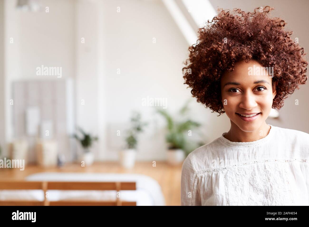 Portrait von Lächelnden jungen Frau in Loft Apartment Stockfoto
