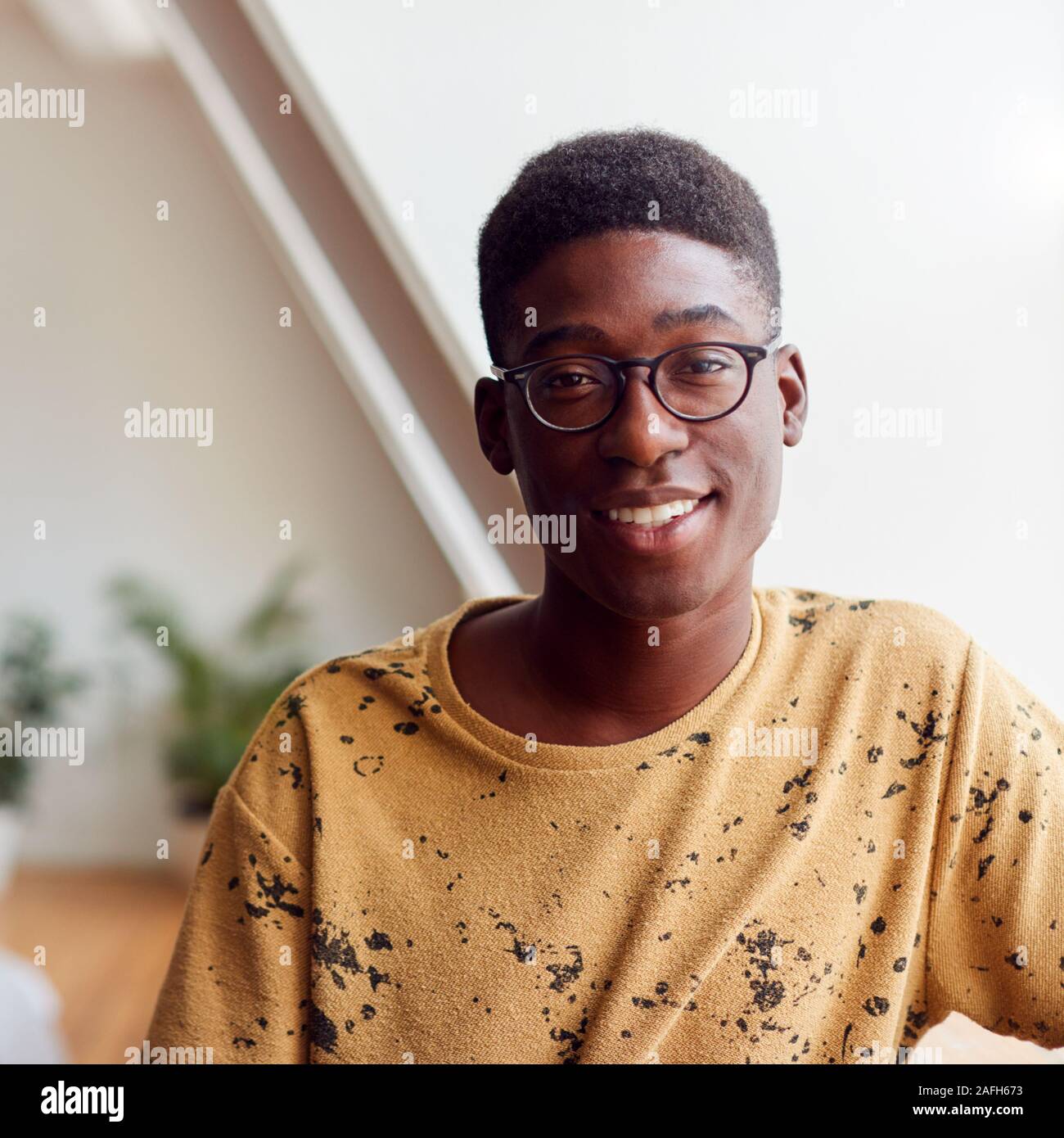 Portrait von Lächelnden jungen Mann in Loft Apartment Stockfoto