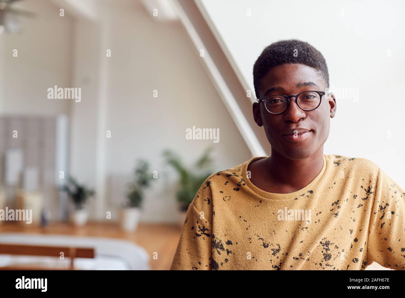 Portrait von Lächelnden jungen Mann in Loft Apartment Stockfoto