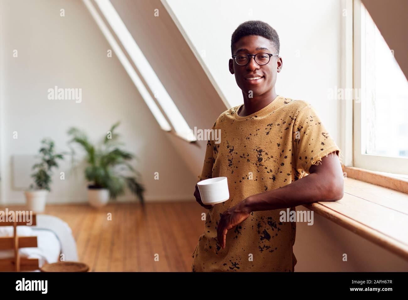 Portrait des jungen Mannes, Entspannen im Loft Apartment mit heißen Getränken Stockfoto