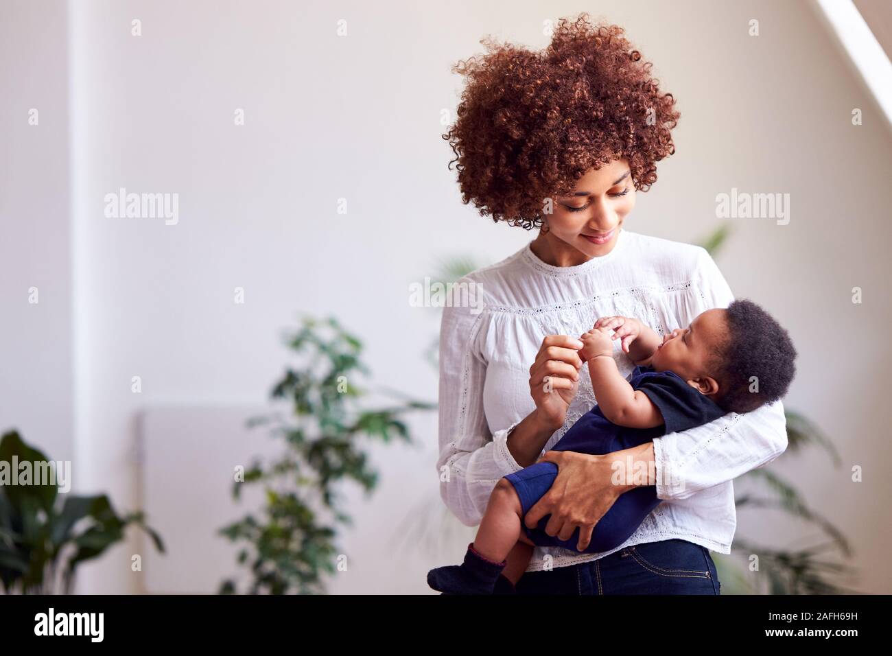 Liebevolle Mutter, neugeborenes Baby zu Hause in Loft Apartment Stockfoto