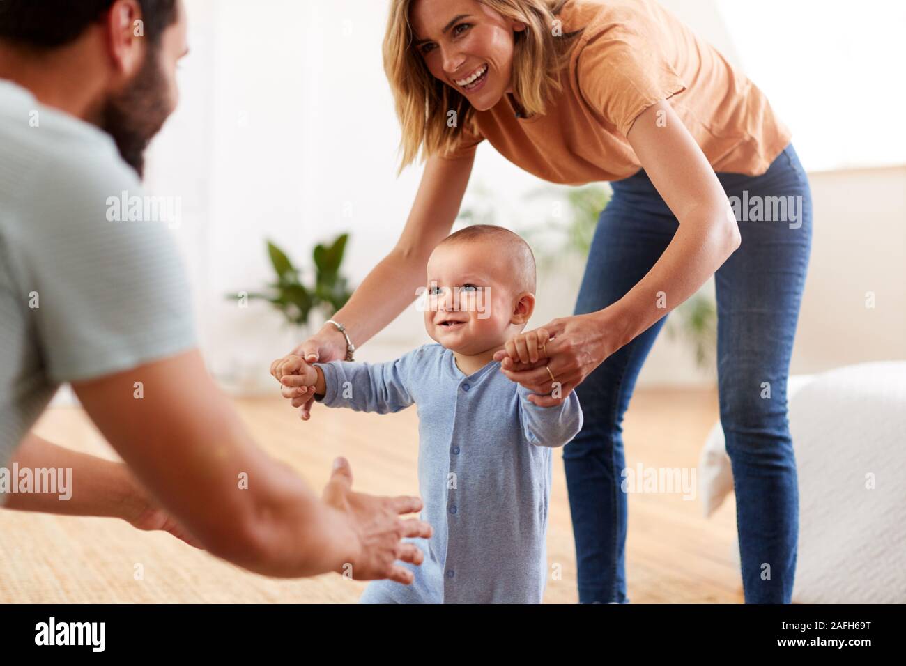 Eltern zu Hause Förderung Baby Sohn Erste Schritte Stockfoto