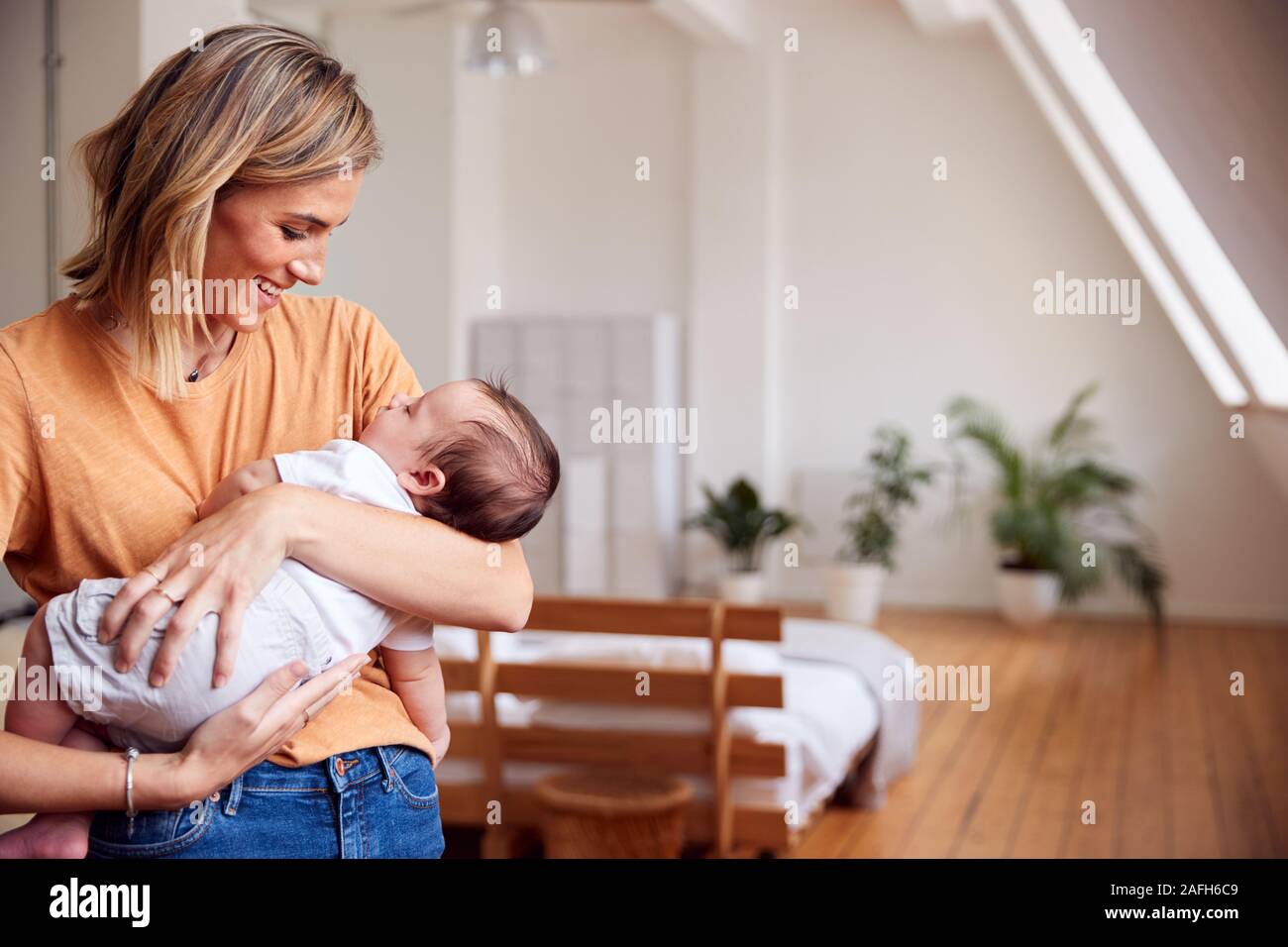 Liebevolle Mutter, neugeborenes Baby zu Hause in Loft Apartment Stockfoto
