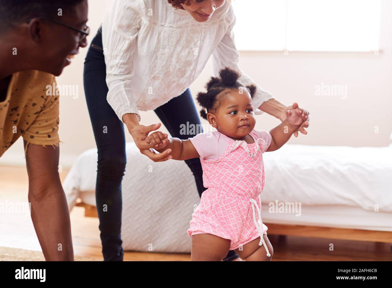 Eltern zu Hause Förderung Baby Tochter Erste Schritte Stockfoto