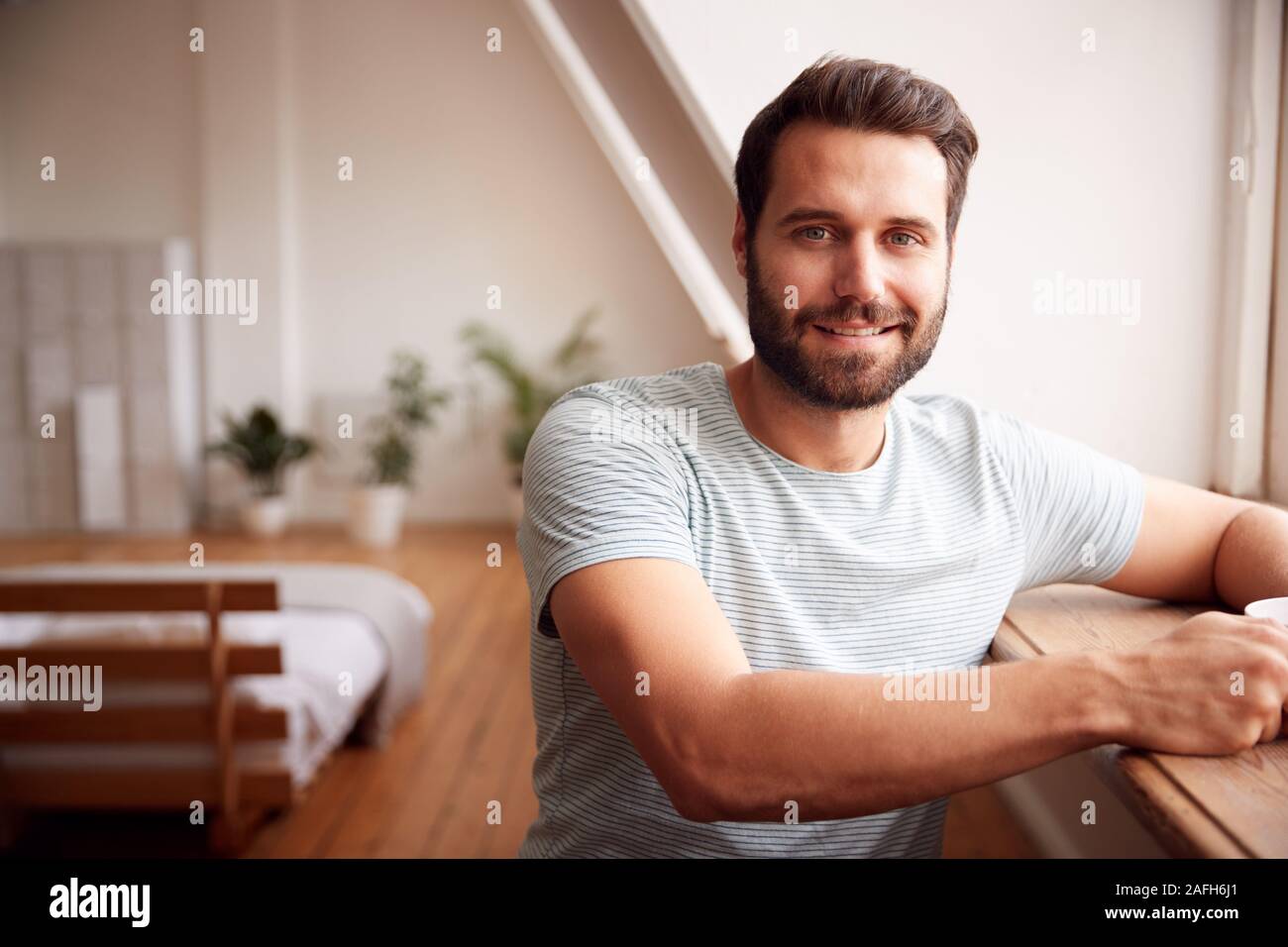 Portrait des jungen Mannes, Entspannen im Loft Apartment mit heißen Getränken Stockfoto
