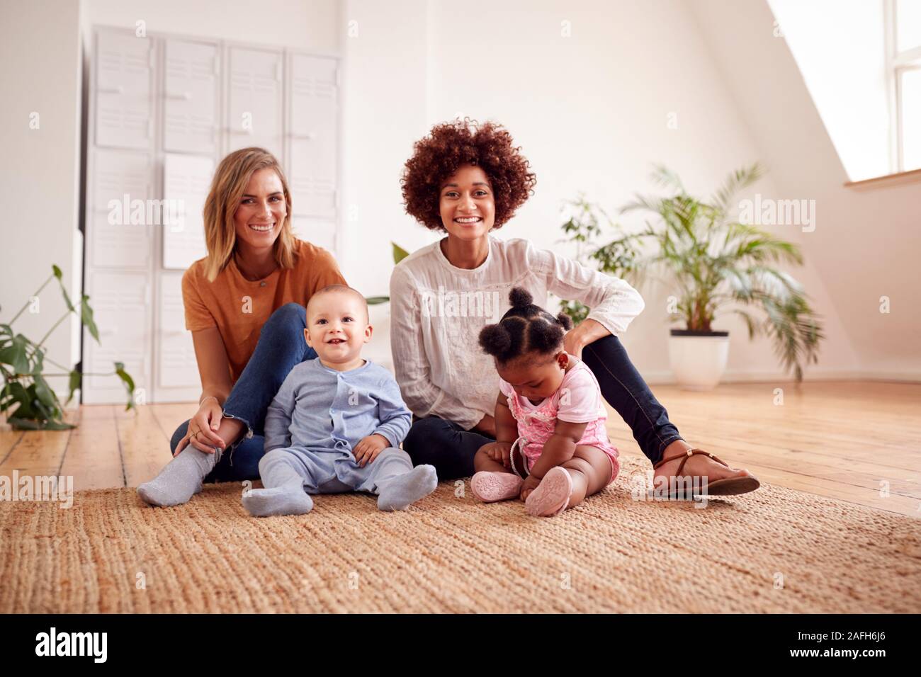 Porträt von zwei Mütter treffen für Spielen mit Babys zu Hause in Loft Apartment Stockfoto