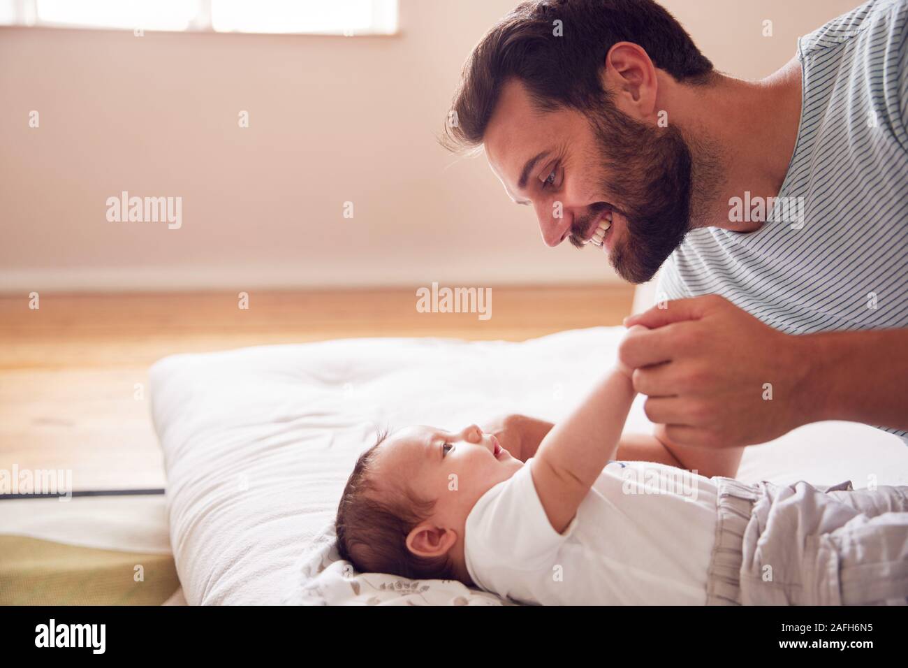 Liebevoller Vater Liegen mit neugeborenen Baby im Bett zu Hause in Loft Apartment Stockfoto