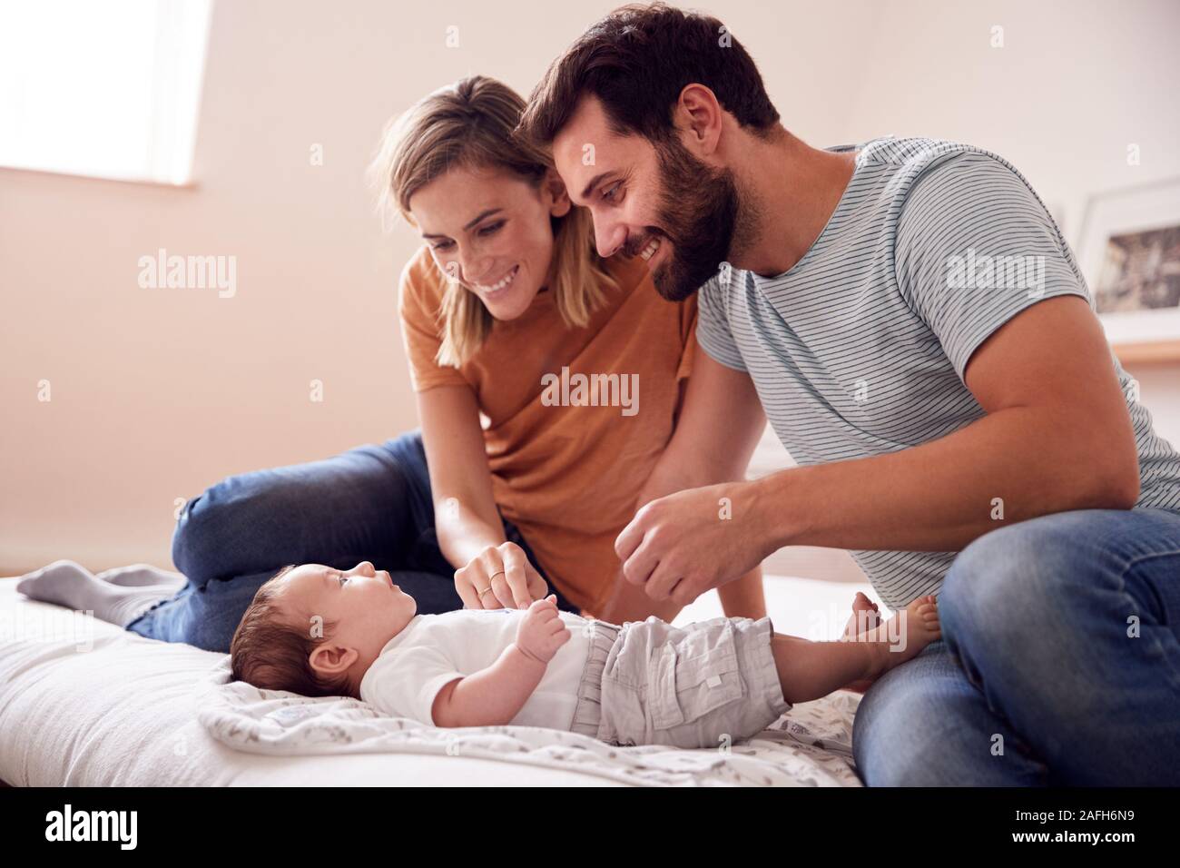 Liebevolle Eltern mit neugeborenen Baby liegend auf Bett zu Hause in Loft Apartment Stockfoto