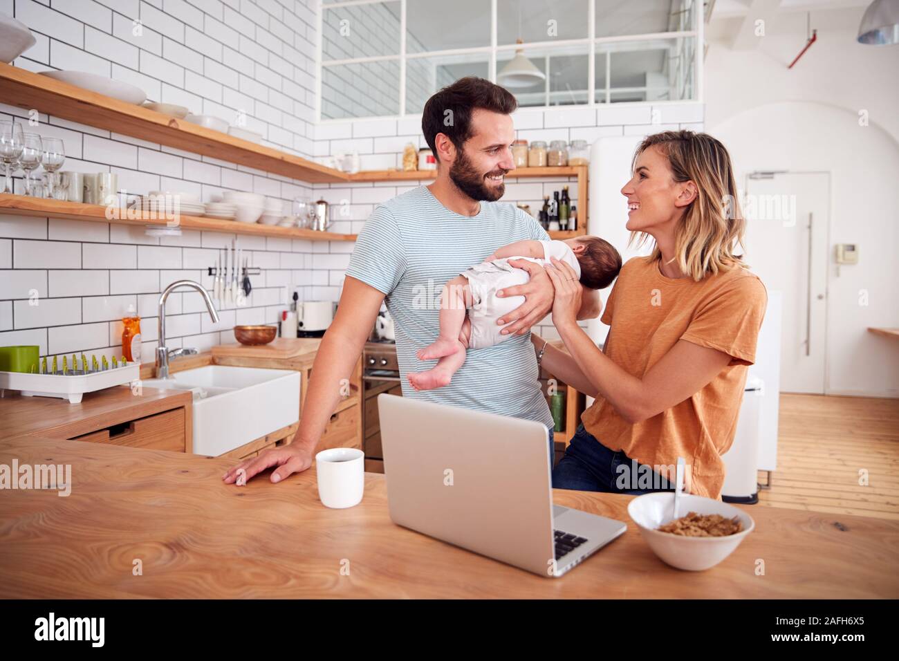 Besetzt die Familie in der Küche beim Frühstück mit Vater Pflege für Baby Sohn Stockfoto