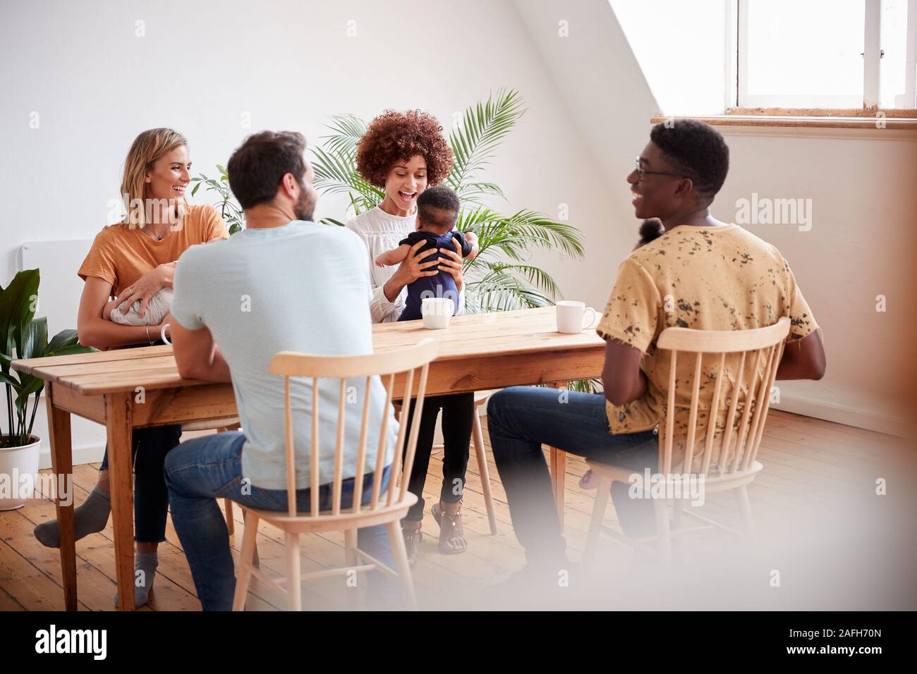 Zwei Familien mit Babys Treffen und Reden um den Tisch zu spielen Datum zu Hause Stockfoto