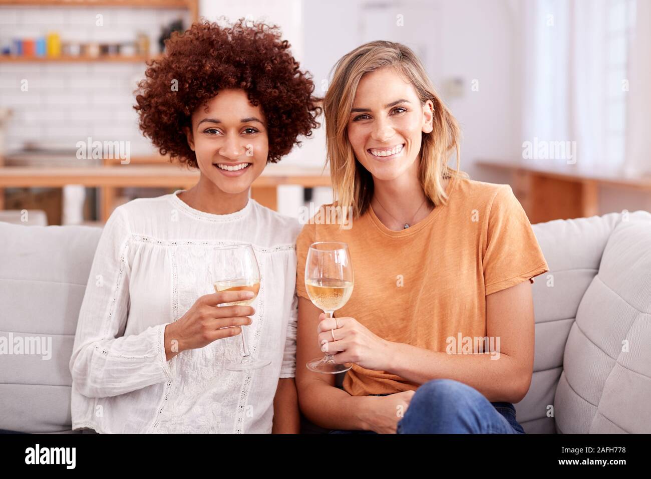 Porträt von zwei weiblichen Freunden entspannen auf dem Sofa zu Hause mit einem Glas Wein Reden Stockfoto