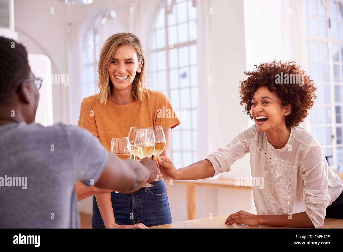 Zwei Paare, die Entspannung in der Küche zu Hause einen Toast mit einem Glas Wein zusammen Stockfoto