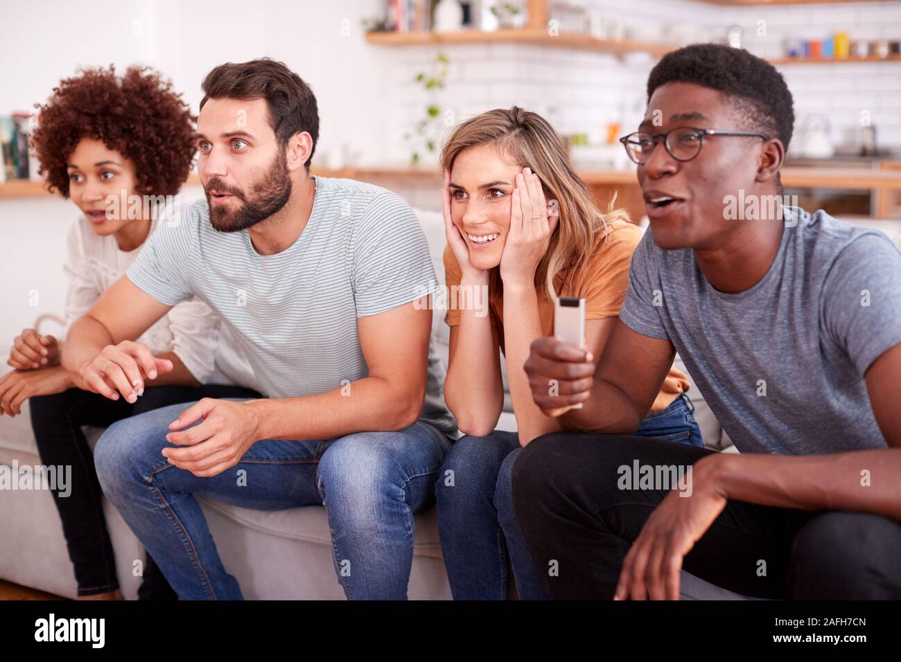 Aufgeregt Gruppe von Freunden sitzen auf dem Sofa und Sport Beobachten auf TV Stockfoto