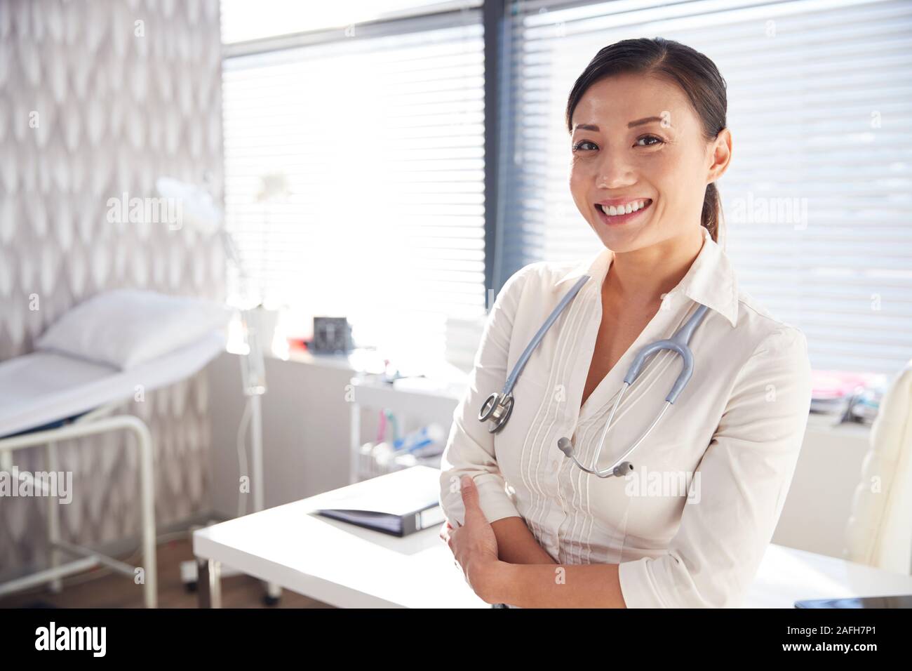 Portrait von lächelnden Frau Doktor mit Stethoskop stehen Schreibtisch im Büro Stockfoto