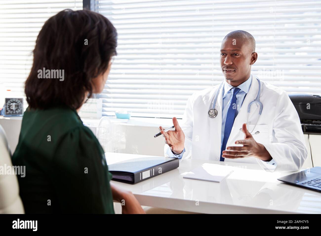 Weibliche Patienten in Absprache mit dem Arzt Sitzen am Schreibtisch im Büro Stockfoto