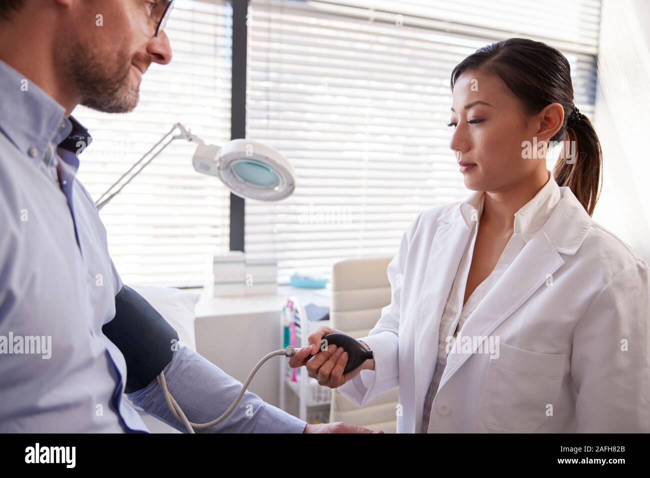 Männliche Patienten, der Blutdruck durch Ärztin in Office Stockfoto
