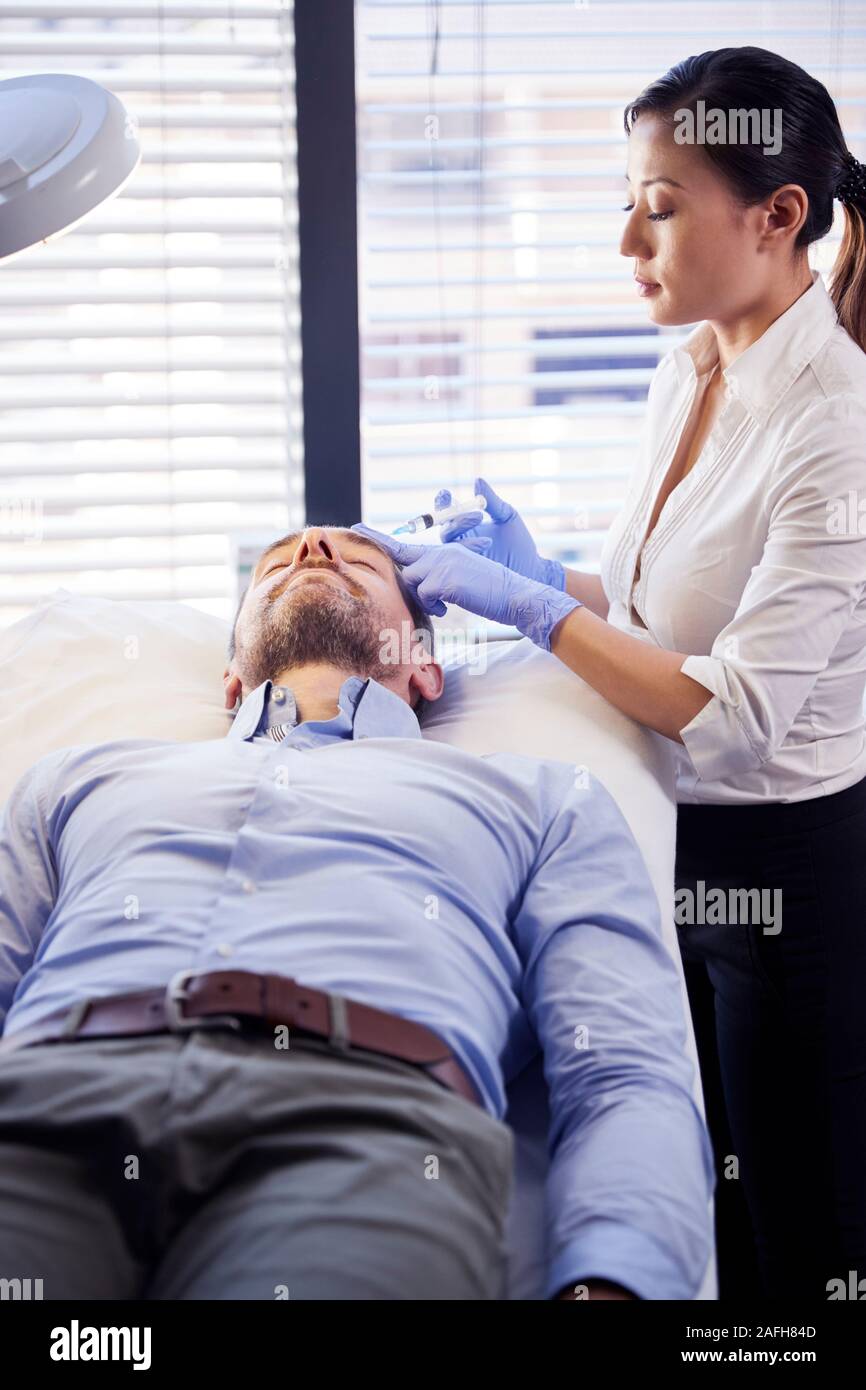 Weibliche Kosmetikerin Geben ältere männliche Patienten Botox Injektion in die Stirn Stockfoto