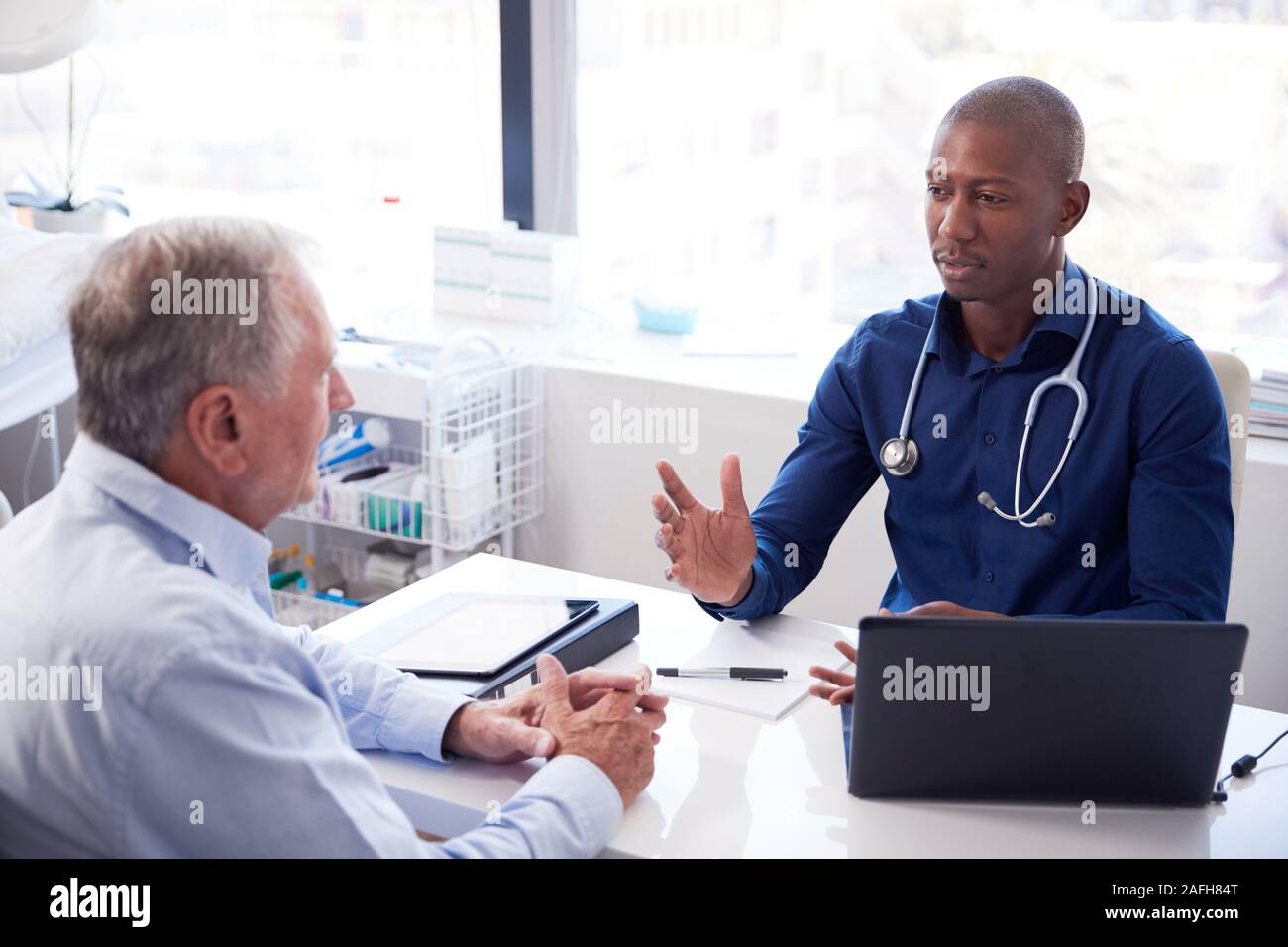 Ältere männliche Patienten in Absprache mit dem Arzt Sitzen am Schreibtisch im Büro Stockfoto