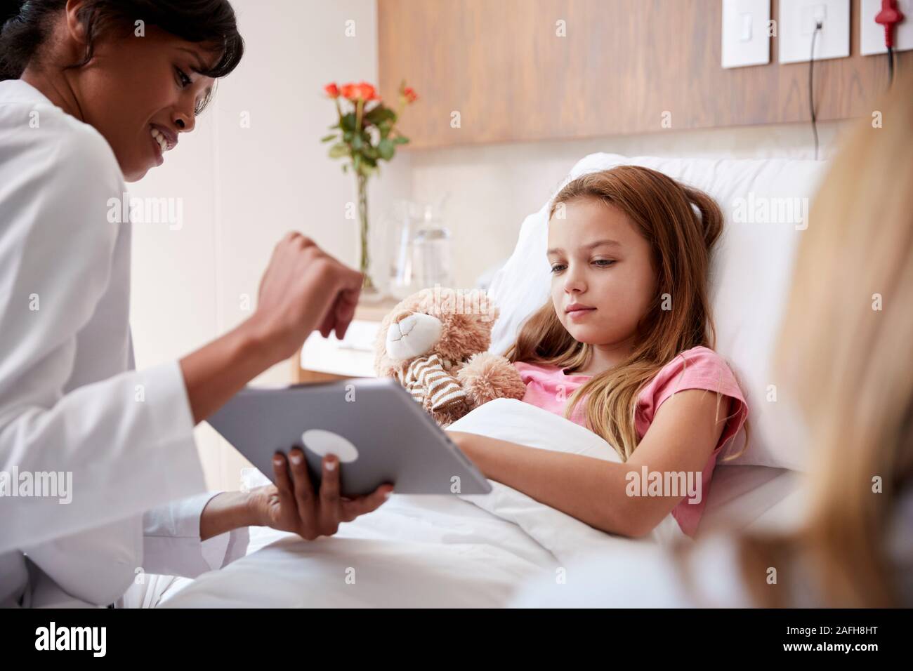 Ärztin, Mutter und Tochter im Bett im Krankenhaus mit digitalen Tablet Stockfoto