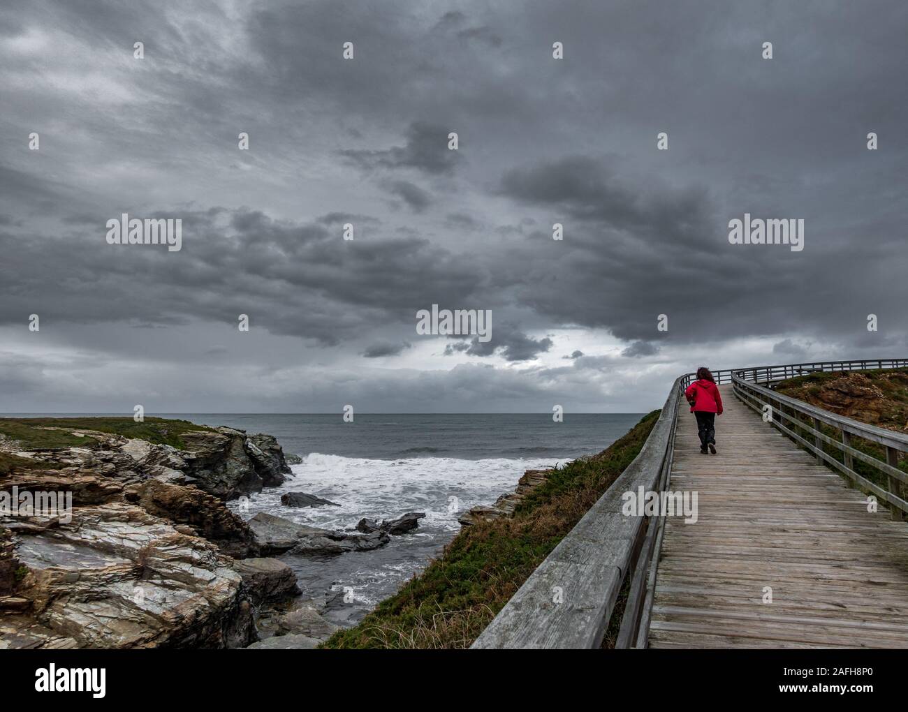 Holz- Anschluss durch den Ozean mit Wanderer unter dem grauen Himmel Stockfoto