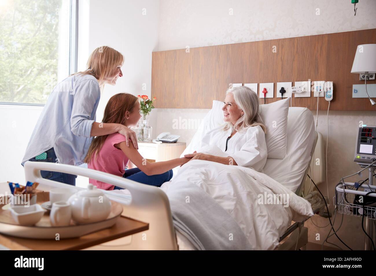 Enkelin Sprechen mit Großmutter auf Familie Besuch im Krankenhaus Stockfoto