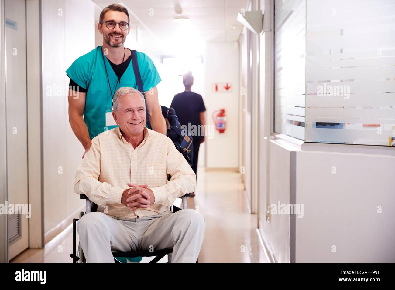Männliche ordentlich Drücken älteren männlichen Patienten, der Entlassung aus dem Krankenhaus im Rollstuhl Stockfoto