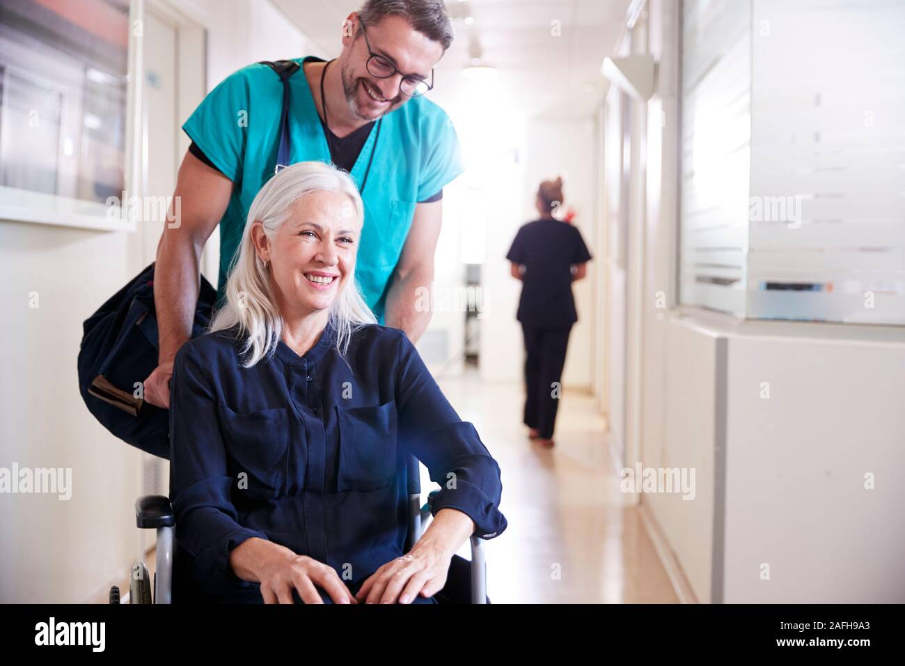 Männliche ordentlich Drücken älteren weiblichen Patienten im Rollstuhl aus dem Krankenhaus entlassen Stockfoto