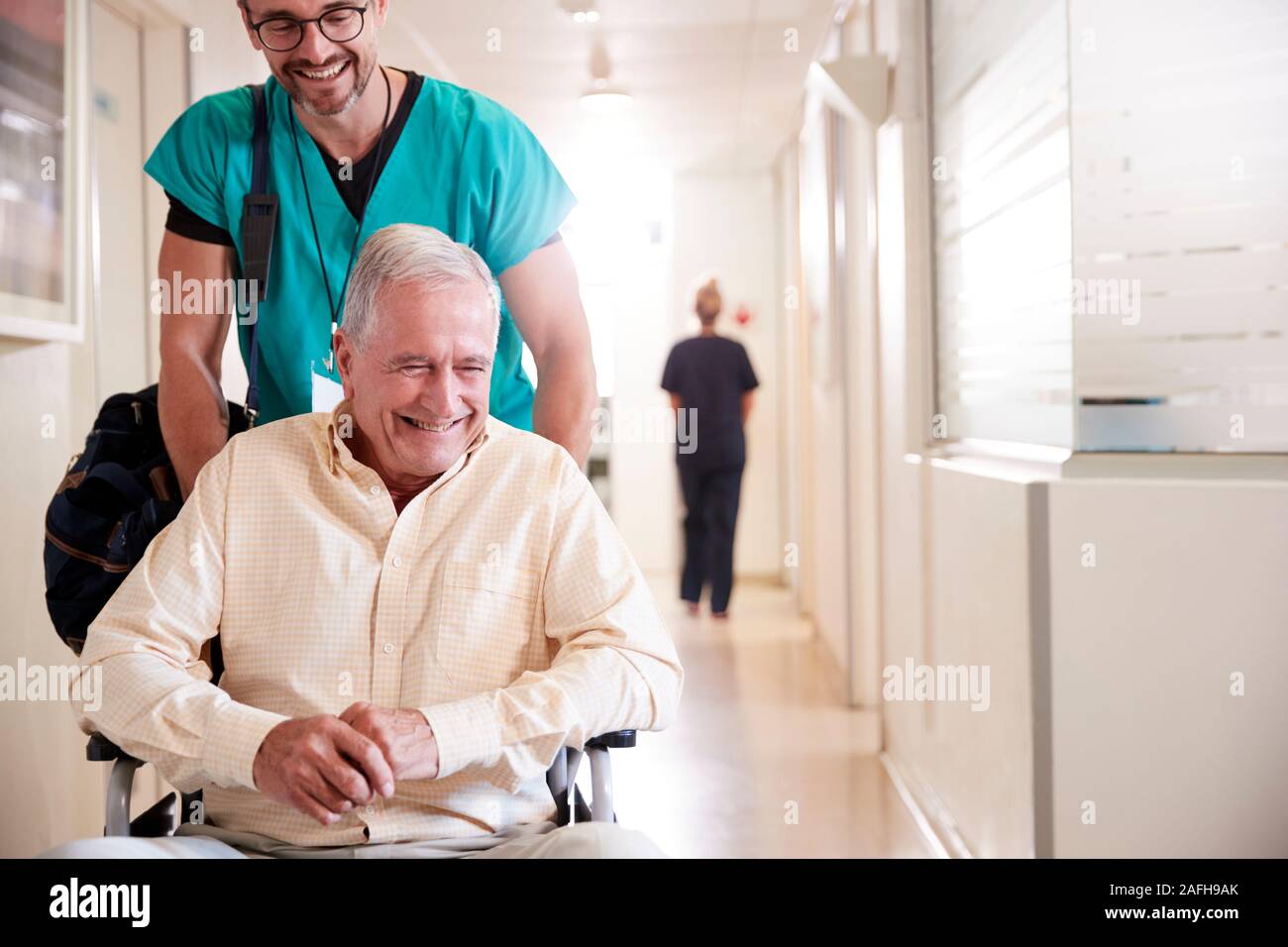 Männliche ordentlich Drücken älteren männlichen Patienten, der Entlassung aus dem Krankenhaus im Rollstuhl Stockfoto