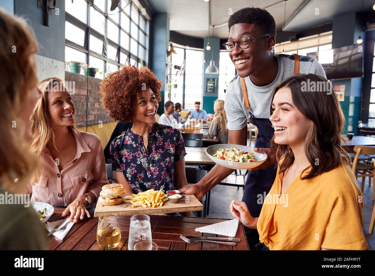 Kellner, die Gruppe der weiblichen Freunde treffen für Getränke und Essen im Restaurant Stockfoto