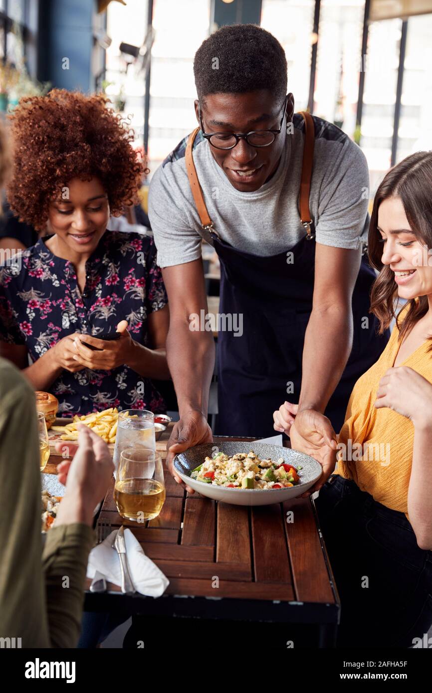Kellner, die Gruppe der weiblichen Freunde treffen für Getränke und Essen im Restaurant Stockfoto