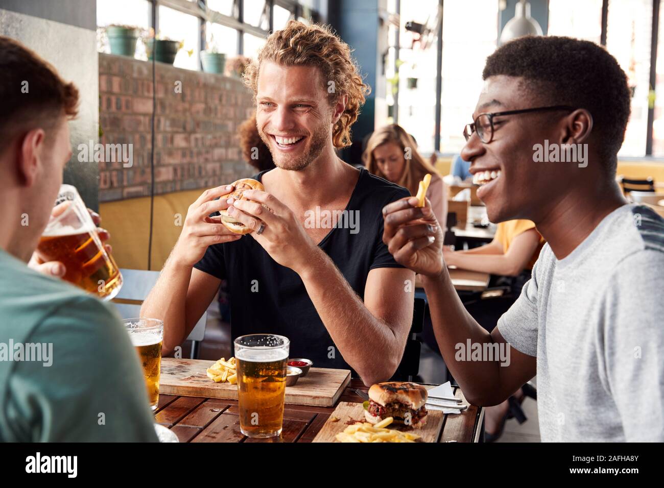 Drei junge männliche Freunde treffen für Getränke im Restaurant Stockfoto