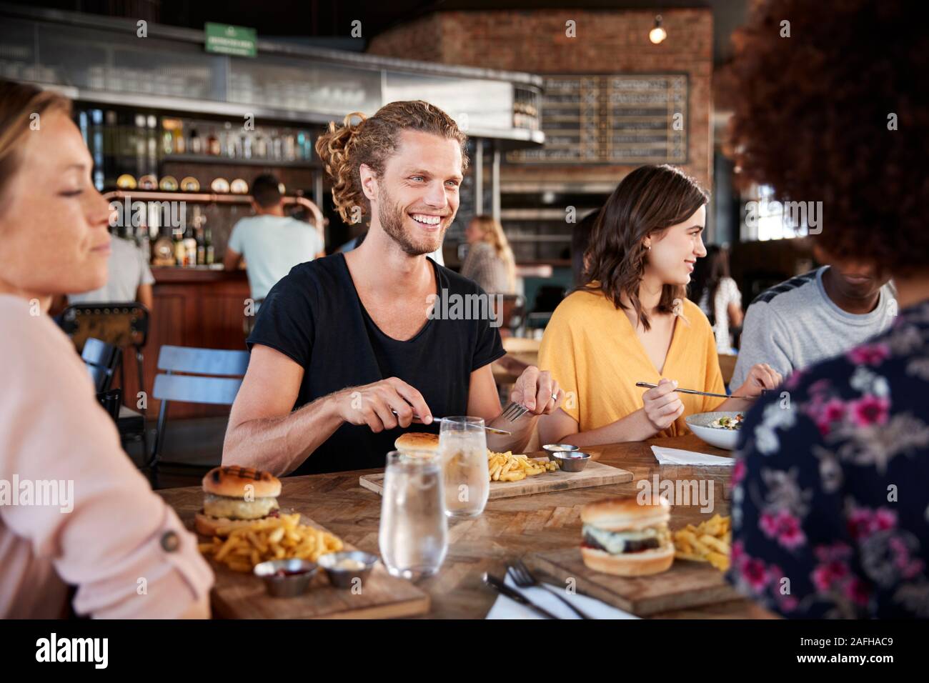 Gruppe junger Freunde treffen für Getränke und Essen im Restaurant Stockfoto