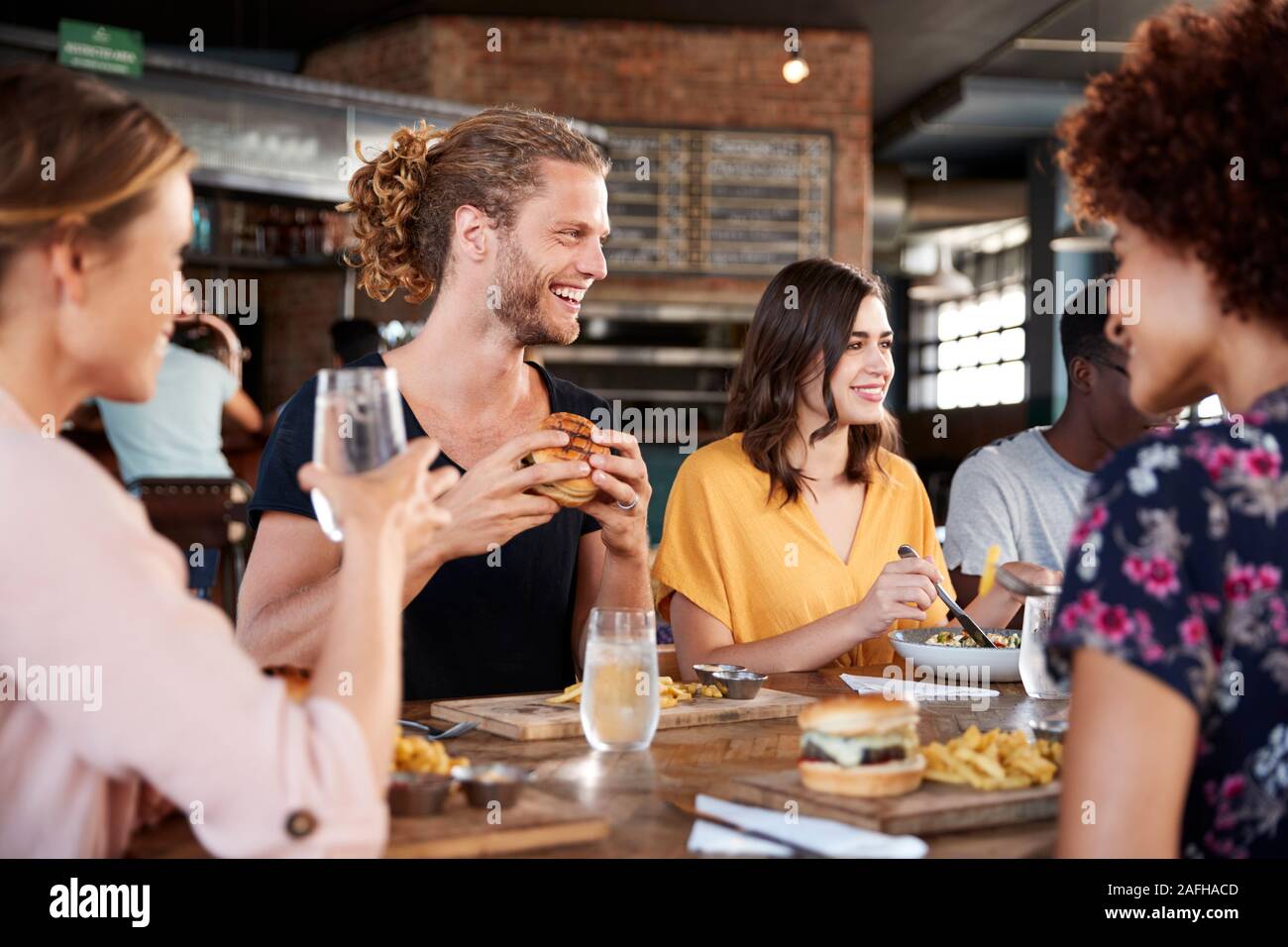 Gruppe junger Freunde treffen für Getränke und Essen im Restaurant Stockfoto