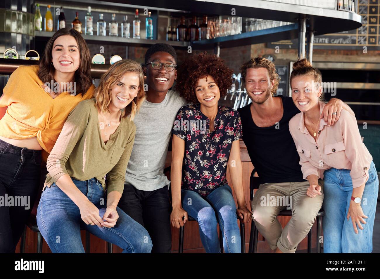 Portrait von männlichen und weiblichen Freunde Sitzen durch Zähler In Sports Bar Stockfoto